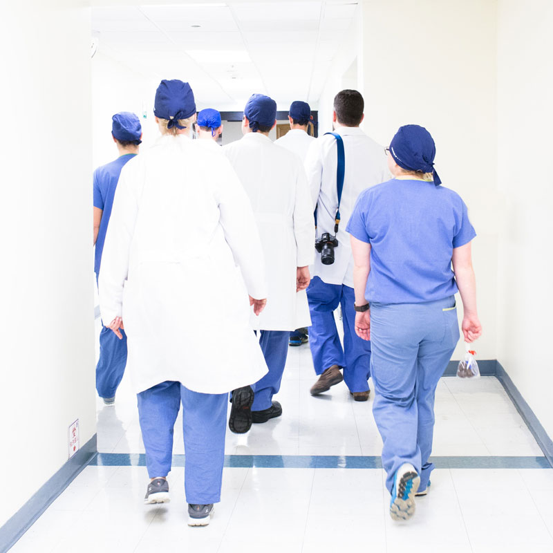 group of healthcare workers walking down a hallway with their backs to the camera